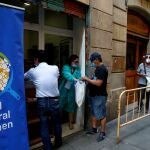 Varias personas hacen cola en Barcelona para recoger menús de comida