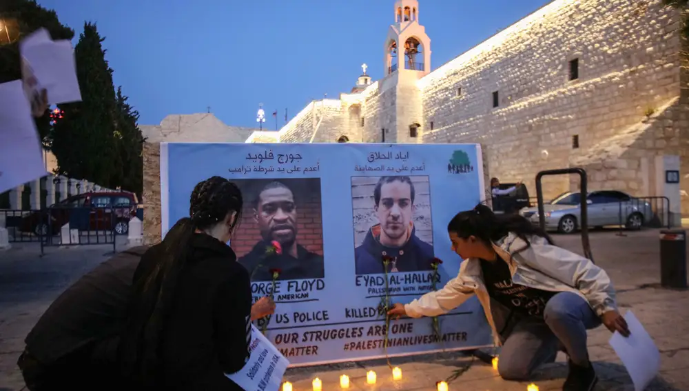 Los manifestantes palestinos sostienen pancartas para mostrar solidaridad por la muerte de George Floyd