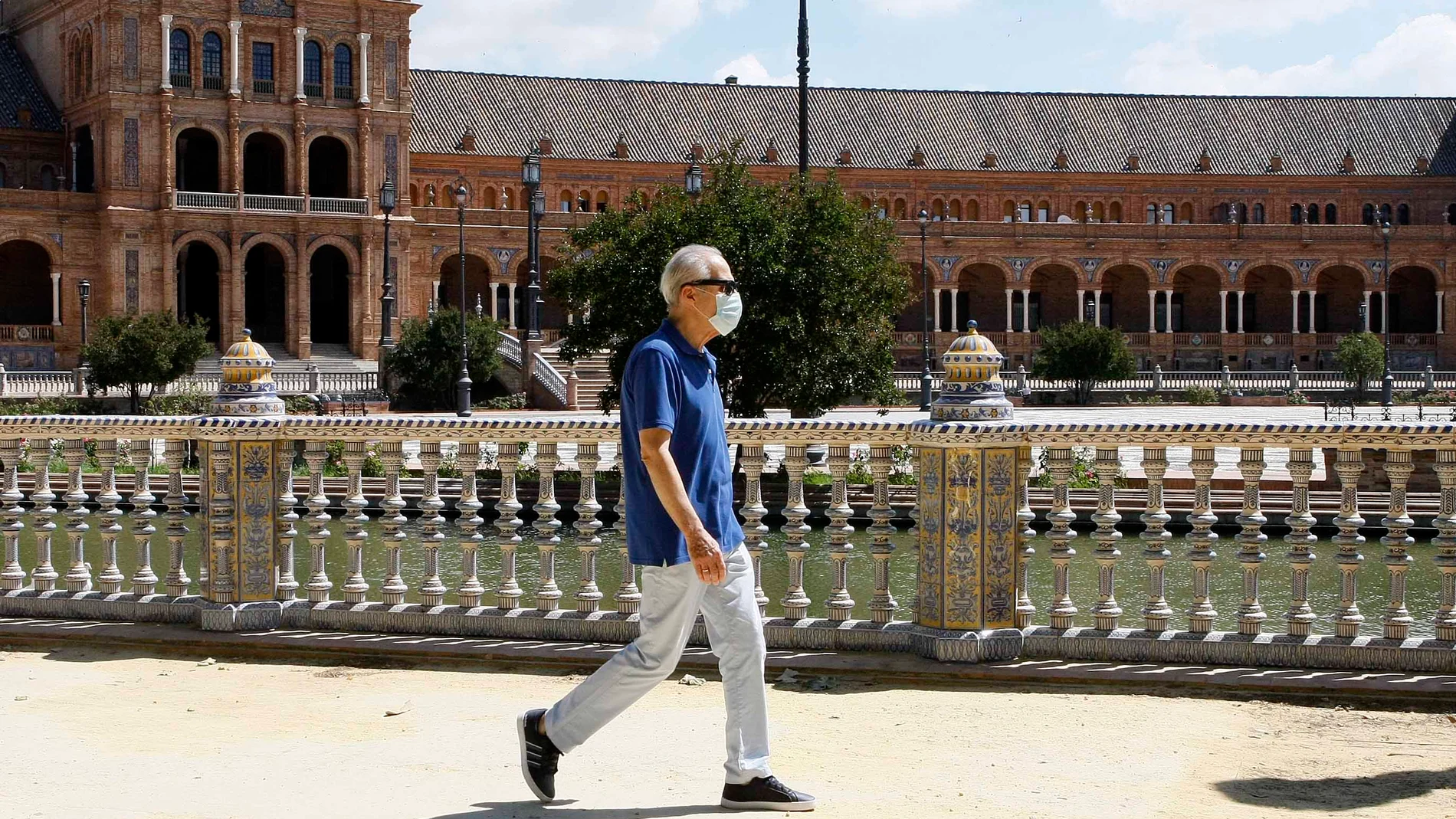 Un ciudadano perteneciente al grupo de riesgo pasea por la Plaza de España de Sevilla