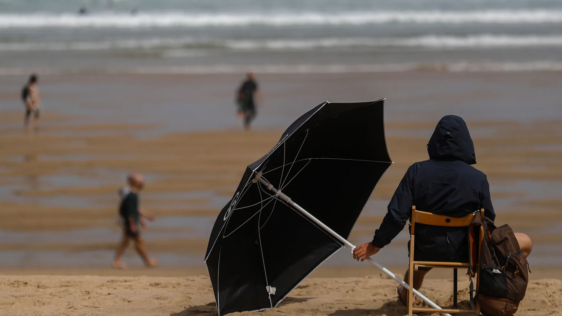 Un joven se protege ayer con un parasol en la playa de la Zurriola de San Sebastián