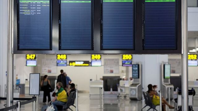 Varias personas esperan para embarcar en el aeropuerto de Málaga en uno de los escasos vuelos previsto ayer