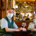 Dos clientes con mascarilla disfrutando del interior de un bar de Segovia en el primer día de la fase 2