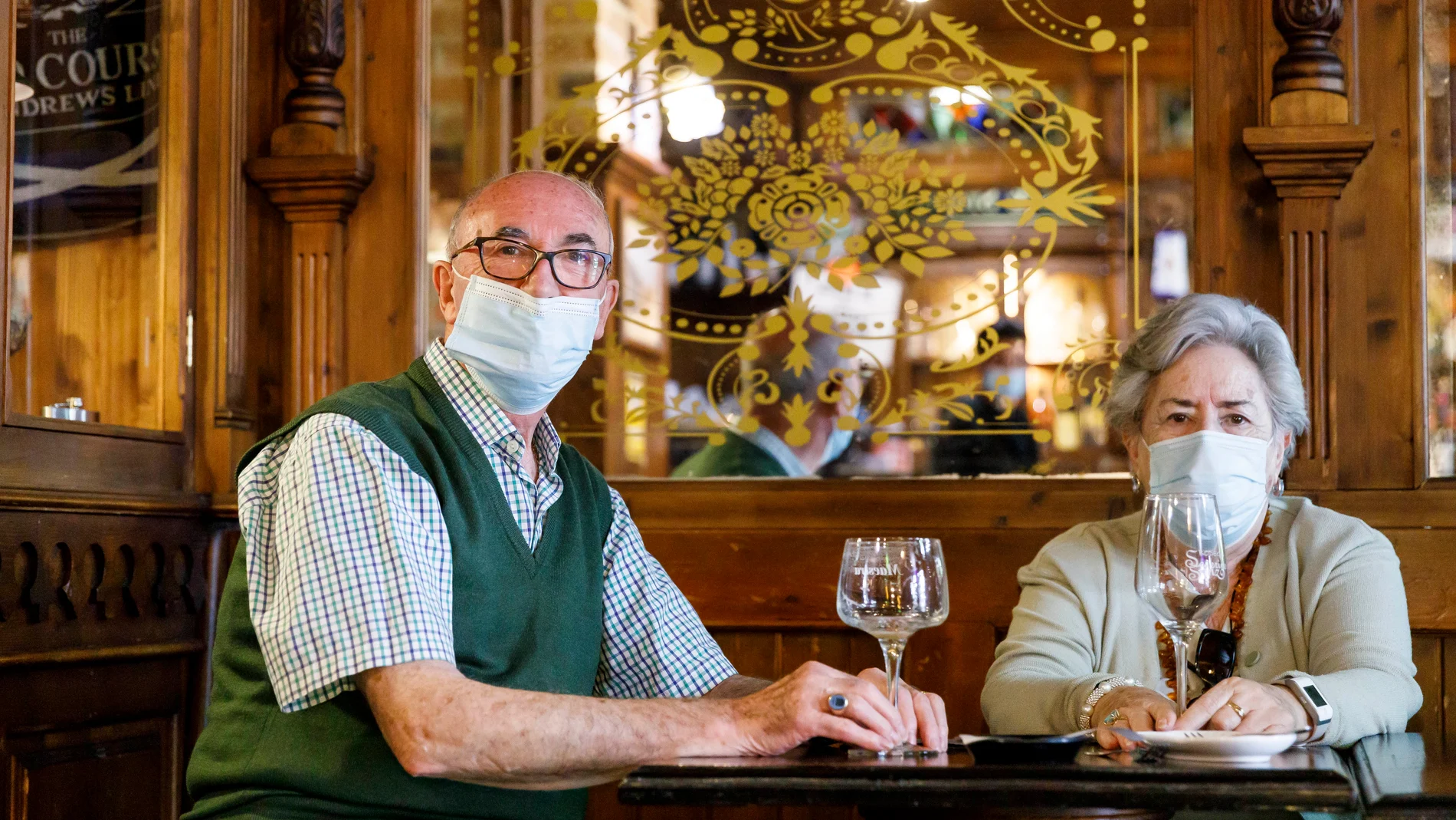 Dos clientes con mascarilla disfrutando del interior de un bar de Segovia en el primer día de la fase 2