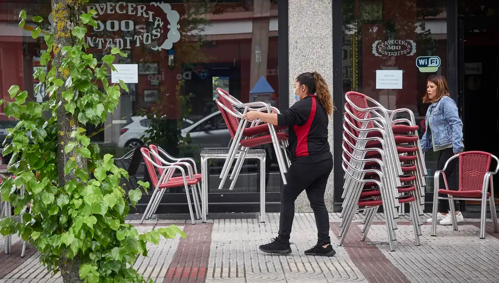 Una camarera prepara la terraza de una cervecería