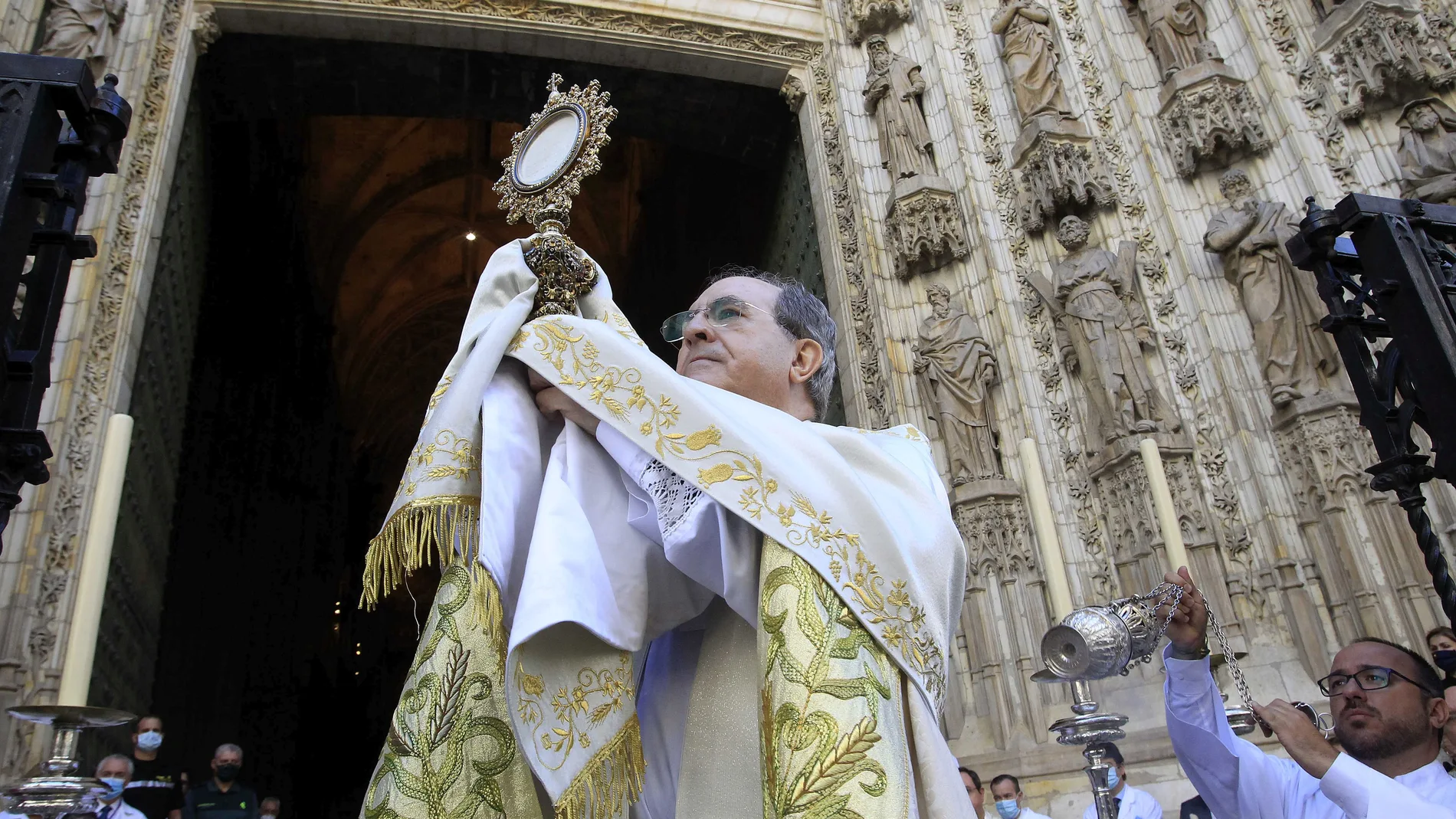 El arzobispo de Sevilla, Juan José Asenjo, bendice a los fieles desde la puerta de la Asunción de la Catedral
