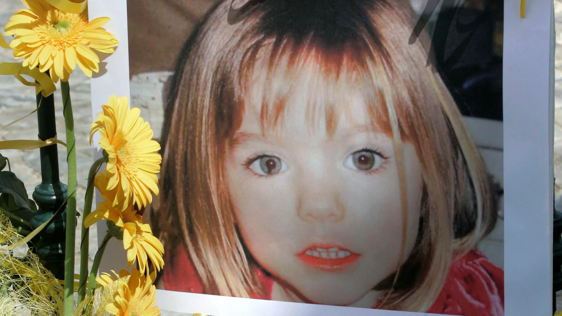 FILE PHOTO: Poster of the missing three-year-old British girl Madeleine McCann is surrounded by flowers and hope-bows in the Portuguese beach resort of Lagos