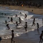 Niños se bañan y divierten hoy en la playa en Barcelona.