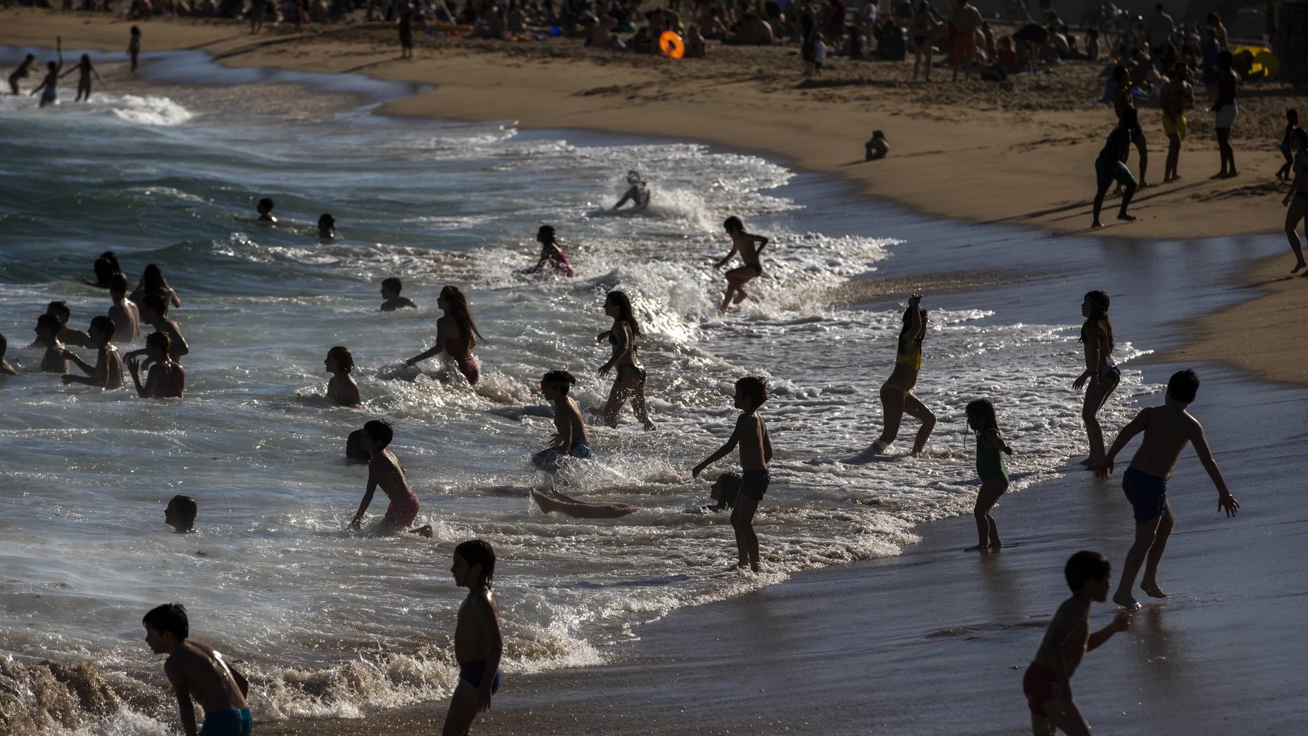 Niños se bañan y divierten hoy en la playa en Barcelona.