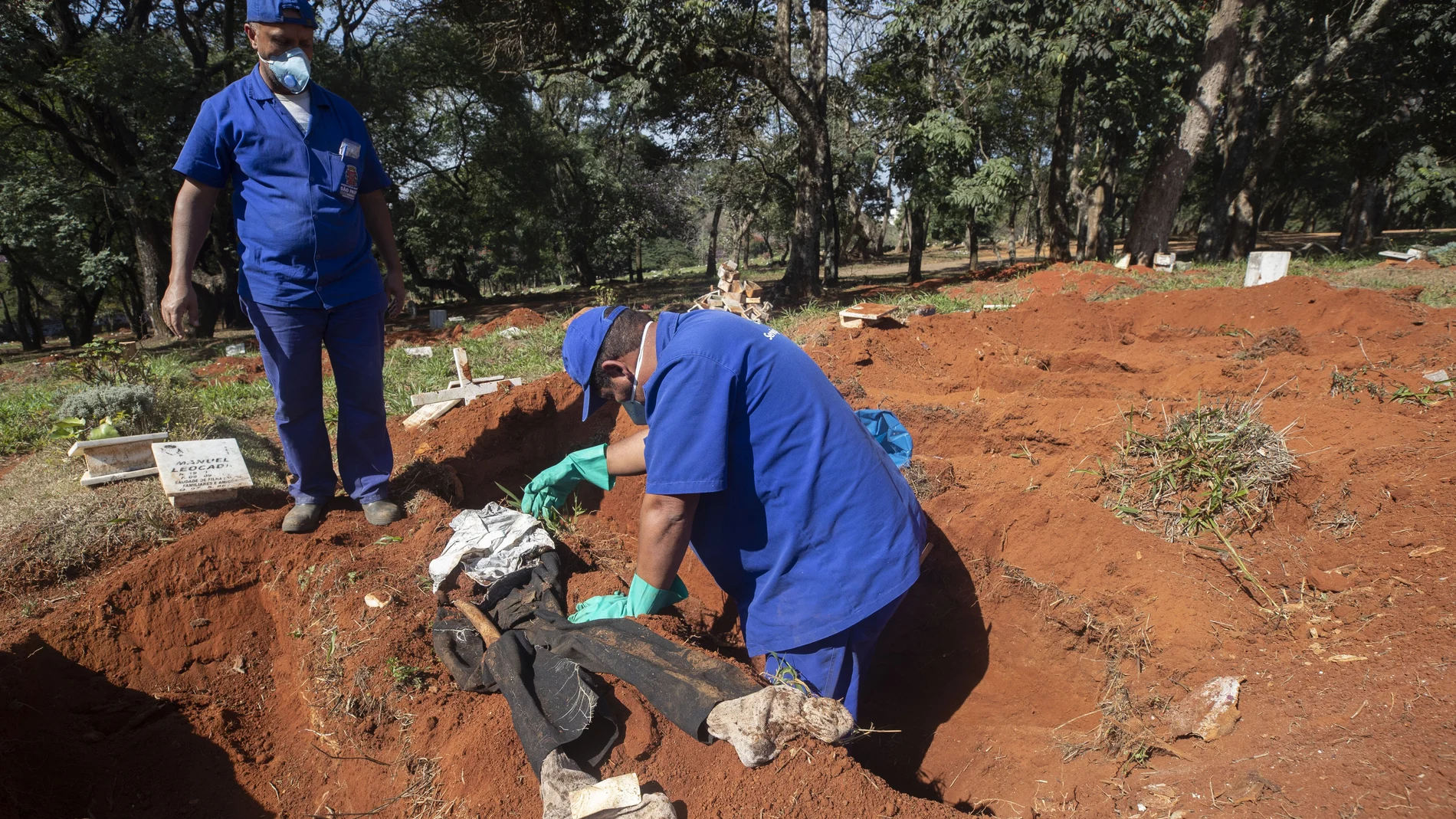 Cemetery workers exhume a body that was buried three years ago at the Vila Formosa cemetery, which does not charge families for the gravesites, in Sao Paulo, Brazil, Friday, June 12, 2020. Three years after burials, remains are routinely exhumated and stored in plastic bags to make room for more burials, which have increased amid the new coronavirus. (AP Photo/Andre Penner)