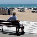 Un hombre descansa en un banco frente a las playas de Benidorm (Alicante)