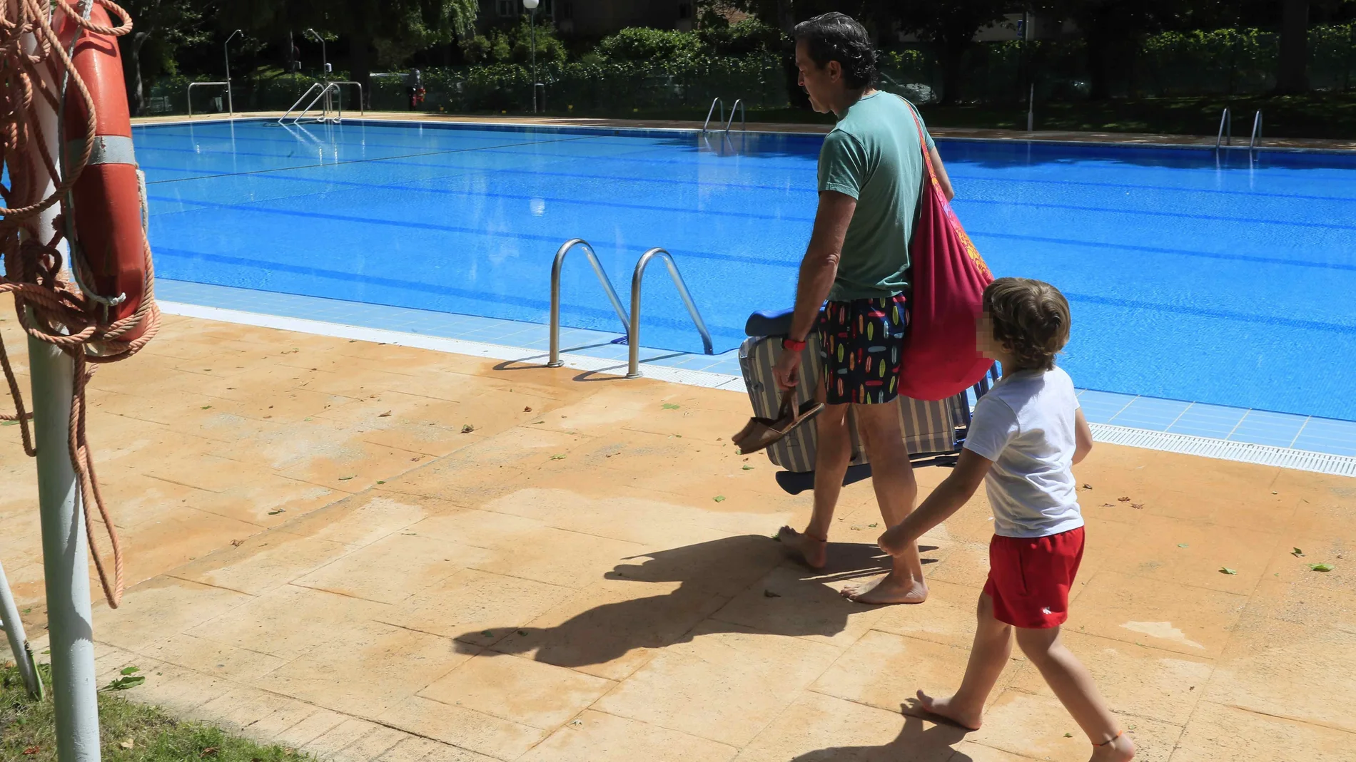 Un padre y un hijo bajan a la piscina comunitaria