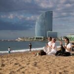 Varias personas meditan en la playa de la Barceloneta a primera hora de la mañana