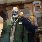 El propietario de una tienda de confección de Palencia coloca mascarillas a sus maniquíes