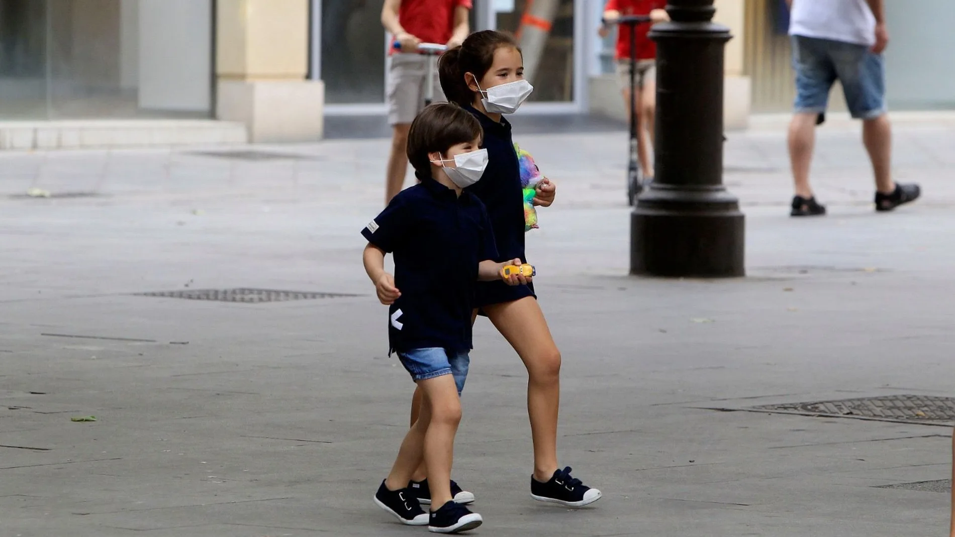 Dos niños, en la calle con mascarillas