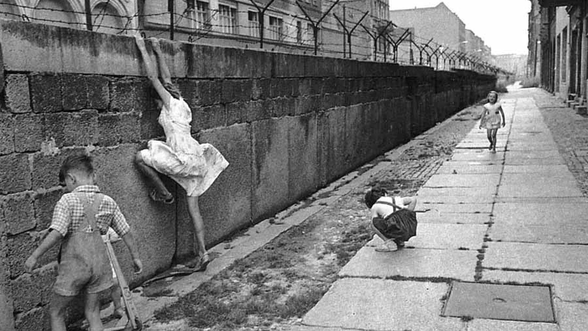 Tres niños juegan con un muro de Berlín que acaba de construirse