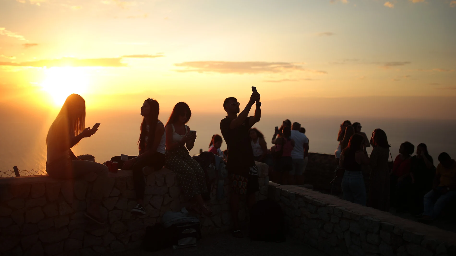 Varios jóvenes disfrutan de una puesta de sol en Palma de Mallorca