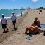 Una pareja de Vigilantes de la playa de Andalucía asesoran a bañistas sobre las medidas preventivas en la playa de La Malagueta durante este verano