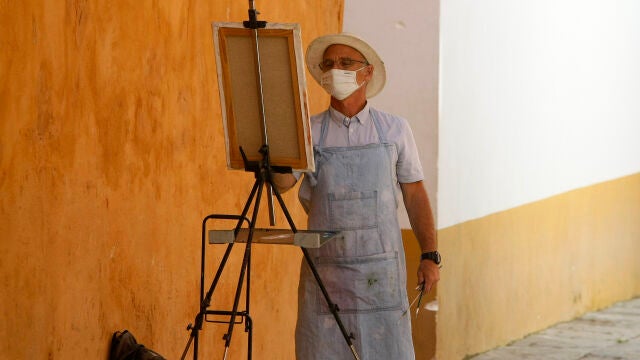 Un pintor callejero de Sevilla realiza sus labores cumpliendo con la normativa de seguridad vigente durante la fase 3 de desescalada
