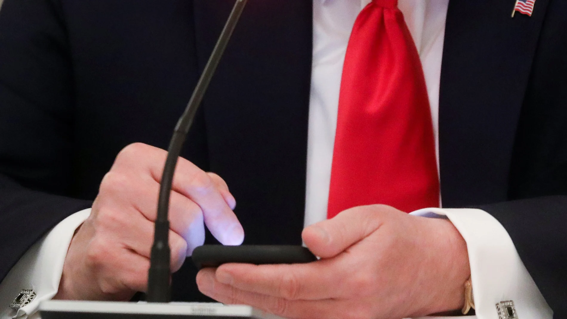U.S. President Donald Trump taps the screen on a mobile phone at the approximate time a tweet was released from his Twitter account, during a roundtable discussion on the reopening of small businesses in the State Dining Room at the White House in Washington, U.S., June 18, 2020. REUTERS/Leah Millis