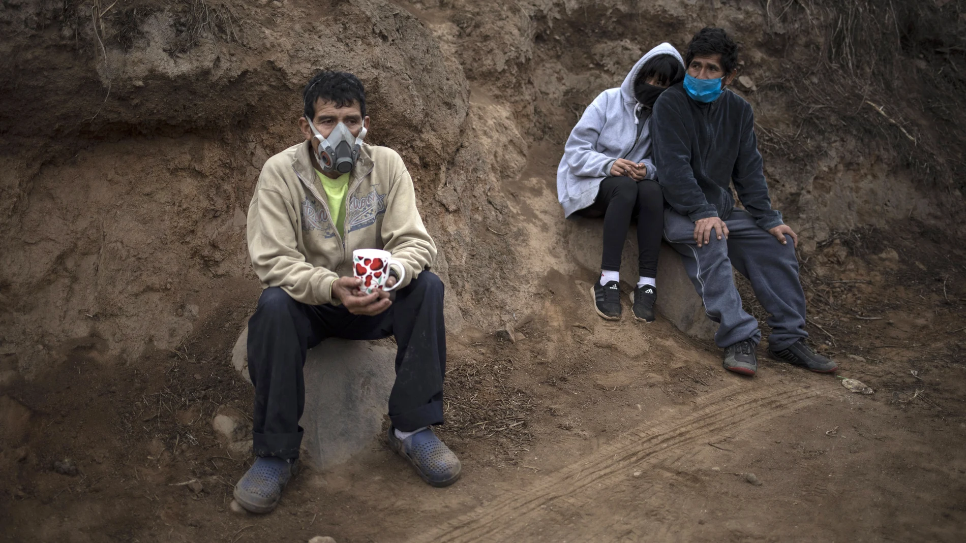 Angel Aguero, left, wearing a mask to curb the spread of the new coronavirus, waits to refill his cup with quinoa donated by a family at the Villa Maria del Triunfo district of Lima, Peru, Wednesday, June 17, 2020. The food was donated by a wealthy family and distributed in a poverty-stricken area of the capital. (AP Photo/Rodrigo Abd)