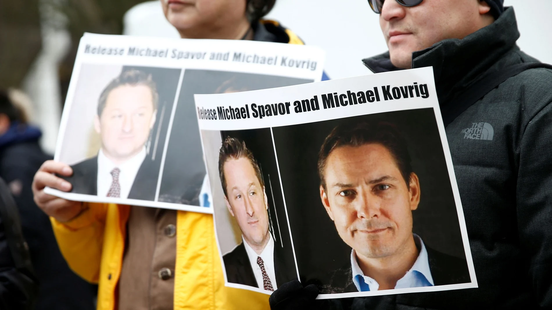 FILE PHOTO: People hold signs calling for China to release Canadian detainees Spavor and Kovrig during an extradition hearing for Huawei Technologies Chief Financial Officer Meng Wanzhou at the B.C. Supreme Court in Vancouver