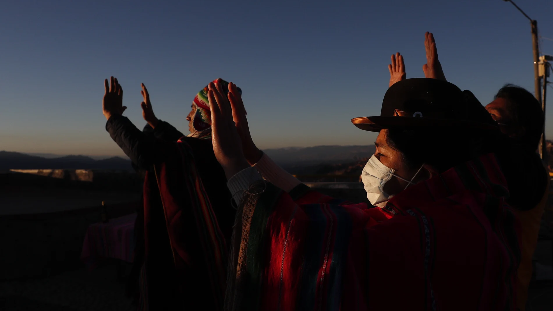 Aymara wearing face masks amid the spread of the new coronavirus, hold up their hands to the first rays of sunlight during a new year's ritual at the Mirador Jach'a Apacheta de Munaypata, in La Paz, Bolivia, early Sunday, June 21, 2020. Aymara indigenous communities are celebrating the Andean new year 5,528. (AP Photo/Juan Karita)