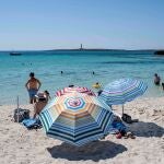 Varias personas disfrutan del buen tiempo en la playa de Punta Prima, Menorca