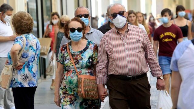 Transeúntes, equipados con mascarillas, pasean por una céntrica calle de Sevilla