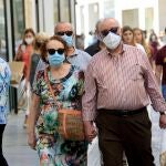 Transeúntes, equipados con mascarillas, pasean por una céntrica calle de Sevilla