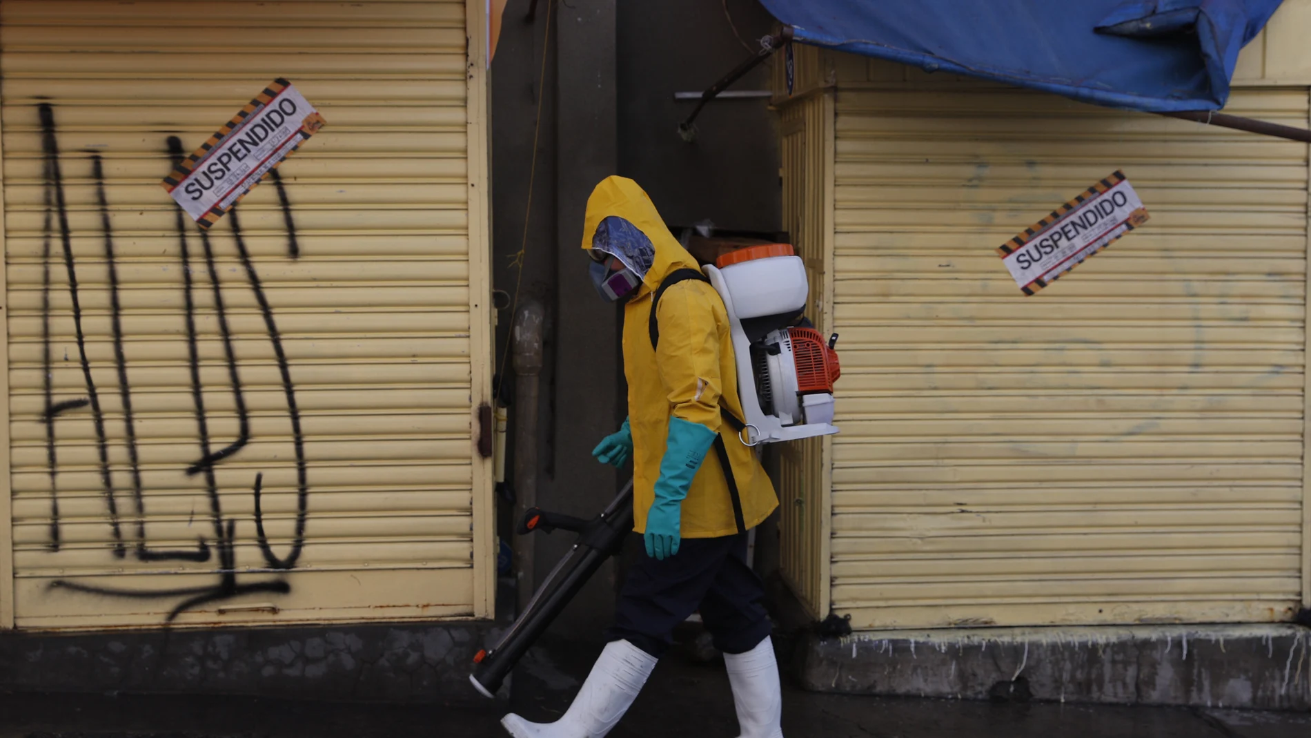 A city worker in full protective gear amid the new coronavirus pandemic disinfects the sidewalk outside the Haiti market in La Paz, Bolivia, Tuesday, June 23, 2020. Health authorities say that a butcher at the marker died several weeks ago of COVID related symptoms, prompting its closure. (AP Photo/Juan Karita)
