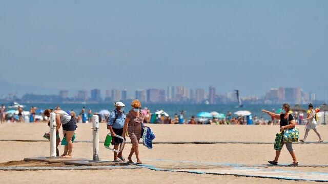Varias personas utilizan un lavapies en la playa de Las Arenas de Valencia