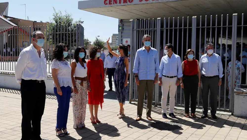 SEVILLA, 29/06/2020.- El rey Felipe VI y la reina Letizia, acompañados por el presidente de la Junta, Juanma Moreno (3d), entre otras autoridades, saludan a un grupo de ciudadanos a su llegada este lunes al centro social Don Bosco en Sevilla. El rey Felipe VI y la reina Letizia visitan lugares emblemáticos de Sevilla y Córdoba en su viaje a Andalucía, tercera parada de su gira autonómica tras el fin del estado de alarma. EFE/Ballesteros