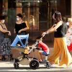 Una madre pasea por la capital hispalense, equipada con mascarilla, tras el fin del estado de alarma