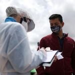 An employee of the Ministry of Health wearing protective gear talks to a man wearing a face mask who will undergo a rapid test for the coronavirus disease (COVID-19), in Bogota, Colombia July 1, 2020. REUTERS/Luisa Gonzalez