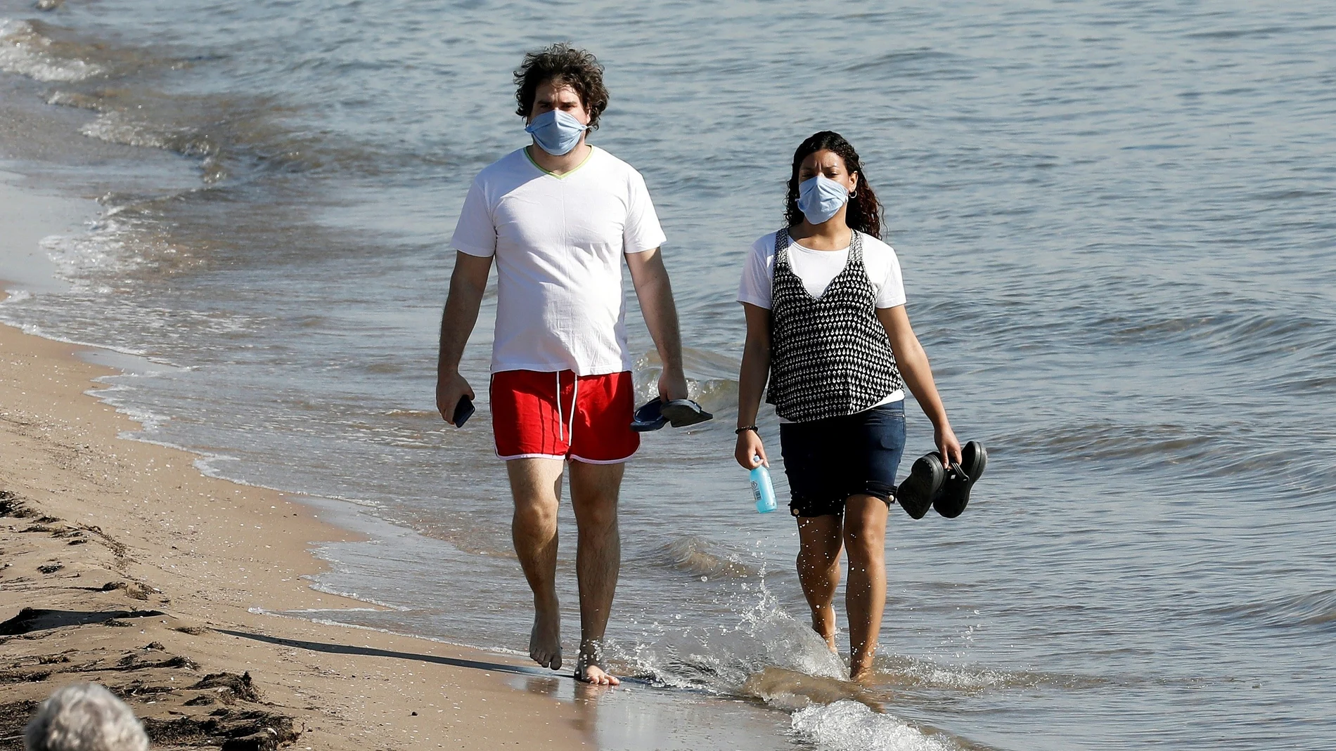 Una pareja protegidas con mascarillas en la playa de la Malvarrosa de Valencia