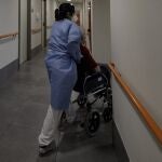 Un técnico sanitario del centro de mayores Casablanca Villaverde lleva a un residente a su habitación