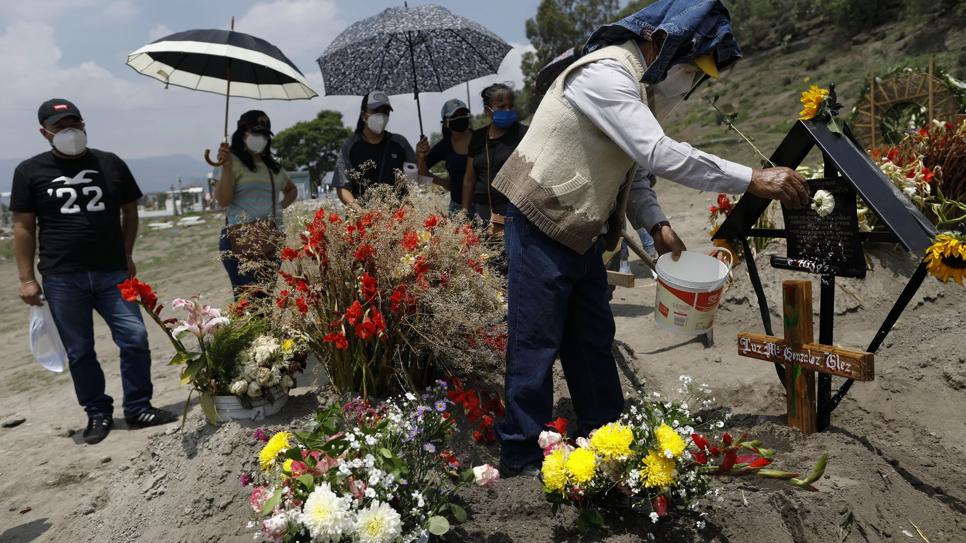 Una familia lleva agua bendita y flores a la tumba Luz María González, a las afueras de Ciudad de México