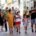 Transeúntes pasean por una céntrica calle de Sevilla equipados con las medidas de protección obligatorias para prevenir contagios