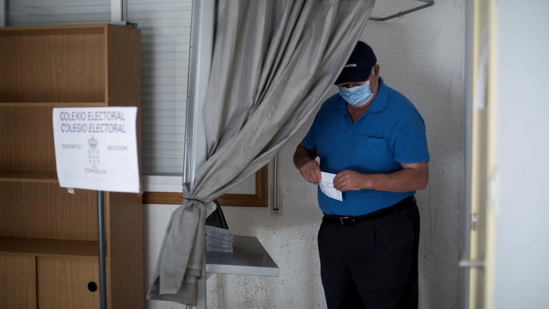 Un hombre coge una papeleta antes de votar en un colegio electoral