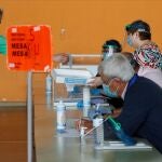 Un hombre vota manteniendo la distancia social en un colegio electoral de Burela (Lugo)