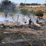 Miembros de los servicios de bomberos extinguen las llamas tras un incendio declarado en un asentamiento chabolista de Lepe, Huelva, este lunes