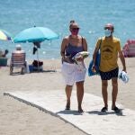 Dos personas abandonan la playa de La Misericordia en Málaga mientras se protegen con mascarillas tras entrar en vigor el uso obligatorio en los espacios abiertos y cerrados por la crisis sanitaria del coronavirus