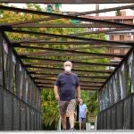 Un hombre camina por el puente que cruza la vía del ferrocarril en L'Hospitalet (Barcelona), este jueves, cuando se han puesto en marcha las medidas especiales de restricción de movimientos adoptadas para contener el brote de COVID-19 en tres barrios de la segunda ciudad más poblada de Cataluña. EFE/Alejandro García