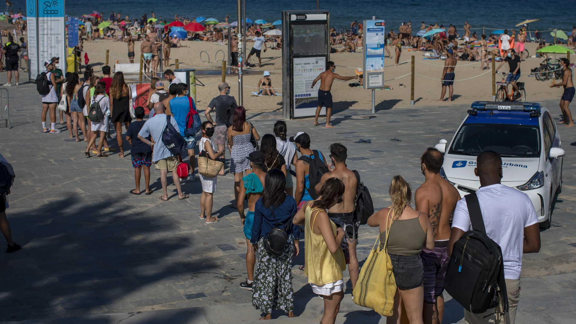 La gente espera para entrar en la playa esta tarde en Barcelona, después de que la Guardia Urbana haya tenido que cerrar algunas debido al elevado número de bañistas.