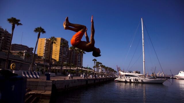 Un joven salta hacia el agua en el Muelle 1 del puerto de Málaga