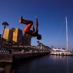 Un joven salta hacia el agua en el Muelle 1 del puerto de Málaga