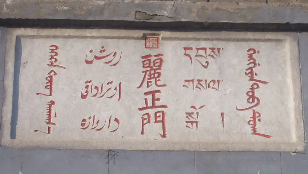 En este cartel podemos ver inscripciones en cinco idiomas diferentes de cuatro familias lingüísticas: de izquierda a derecha, mongol (familia mongólica), chagatai (familia túrquica), chino y tibetano (familia chino-tibetana) y manchú (familia tungús). La escritura chagatai, como podemos ver, está basada en la árabe (a través del persa), mientras que la escritura manchú proviene de la mongólica. El cartel está instalado en la residencia de verano de Chengde, construida por los emperadores chinos de la dinastía Qing en el siglo XVIII, y simplemente indica el nombre de una puerta: la Puerta de la Belleza y la Virtud.