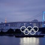 Los aros olímpicos iluminan el agua cerca del Puente del Arco Iris en el Parque Marino de Odaiba