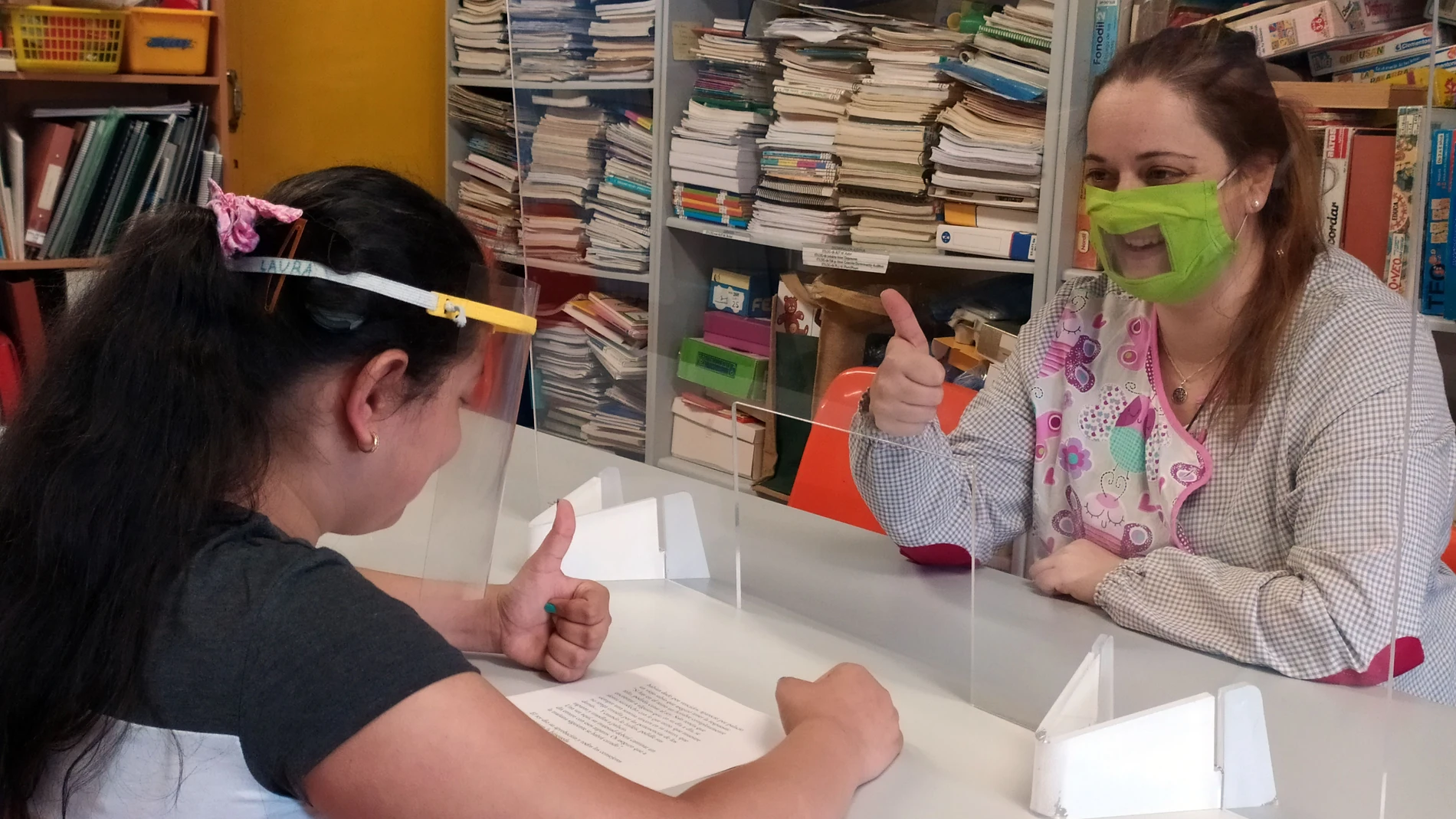 Usuaria y profesora de Aransbur se protegen con una mampara transparente durante una de las sesiones de rehabilitación del lenguaje para niños y adultos con deficiencia auditiva