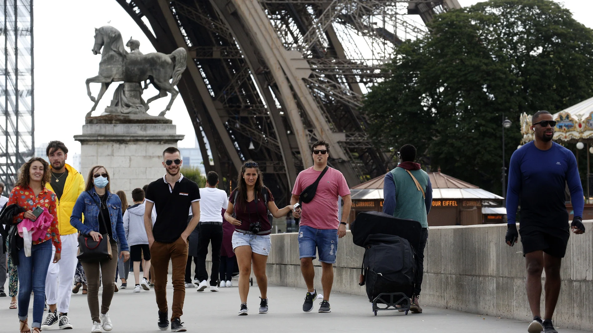 Turistas caminando junto a la torre Eiffel